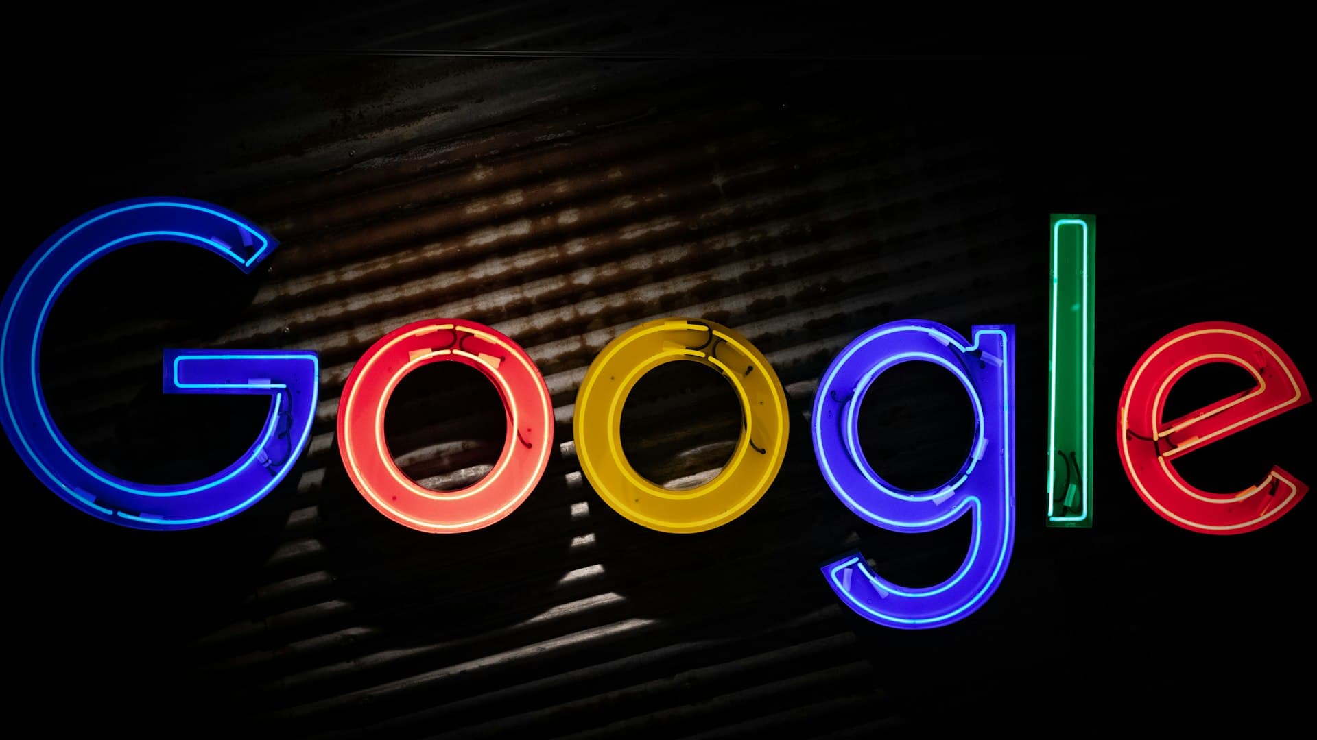 Letreiro neon do Google iluminado em cores vibrantes contra fundo escuro