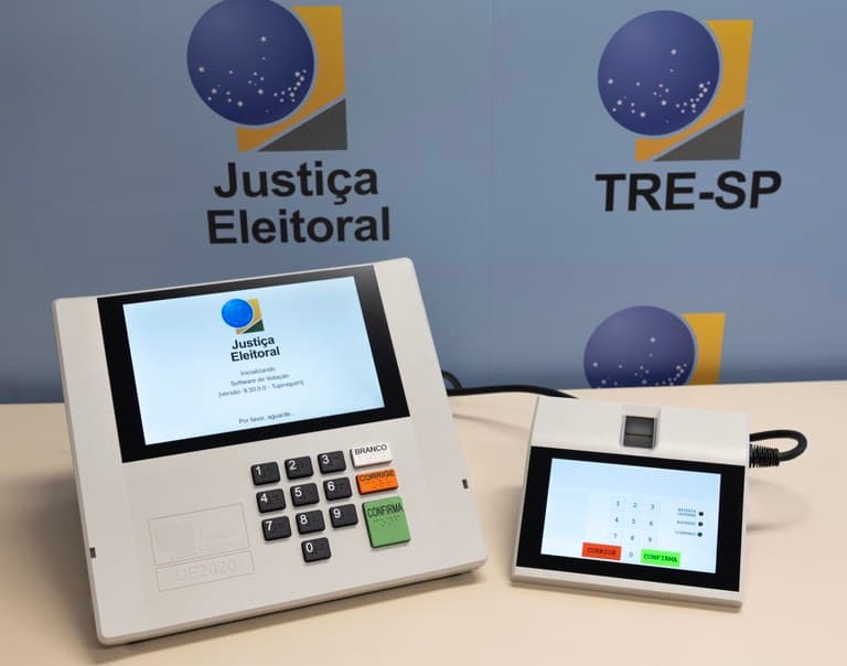Urna eletrônica brasileira com teclado numérico e tela da Justiça Eleitoral, equipamento usado nas eleições 2026